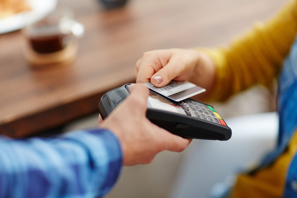 Gros plan d'un client méconnaissable choisissant le paiement sans contact par carte de crédit tandis que la serveuse accepte le paiement par technologie nfc